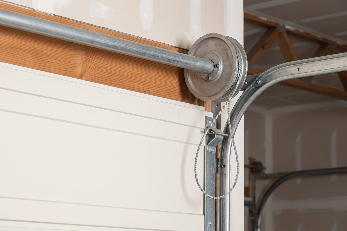 A lift cable that has jumped its drum groove, leaving a slack loop down the edge of the door.