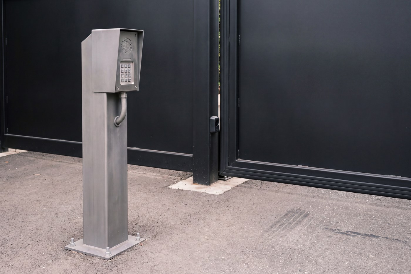 A driveway entry pedestal on its base plate, with a speaker grille and a plain unmarked keypad.