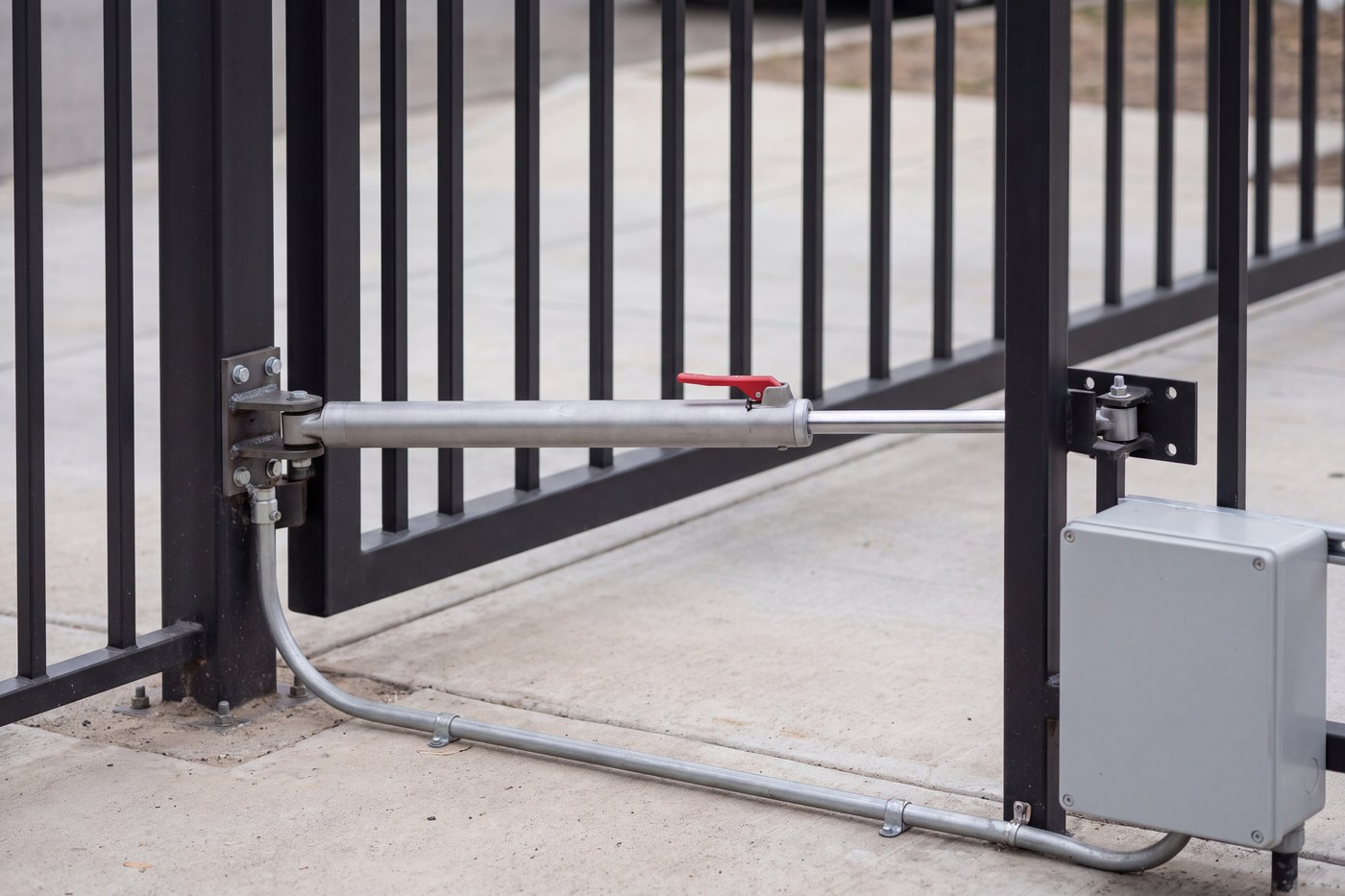 A swing gate actuator at full extension between its post bracket and gate bracket, conduit terminated.